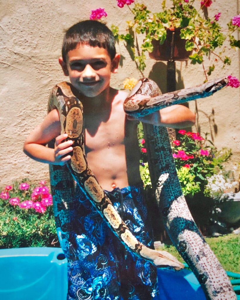 Jonathan as a young child holding his family's pet snakes.